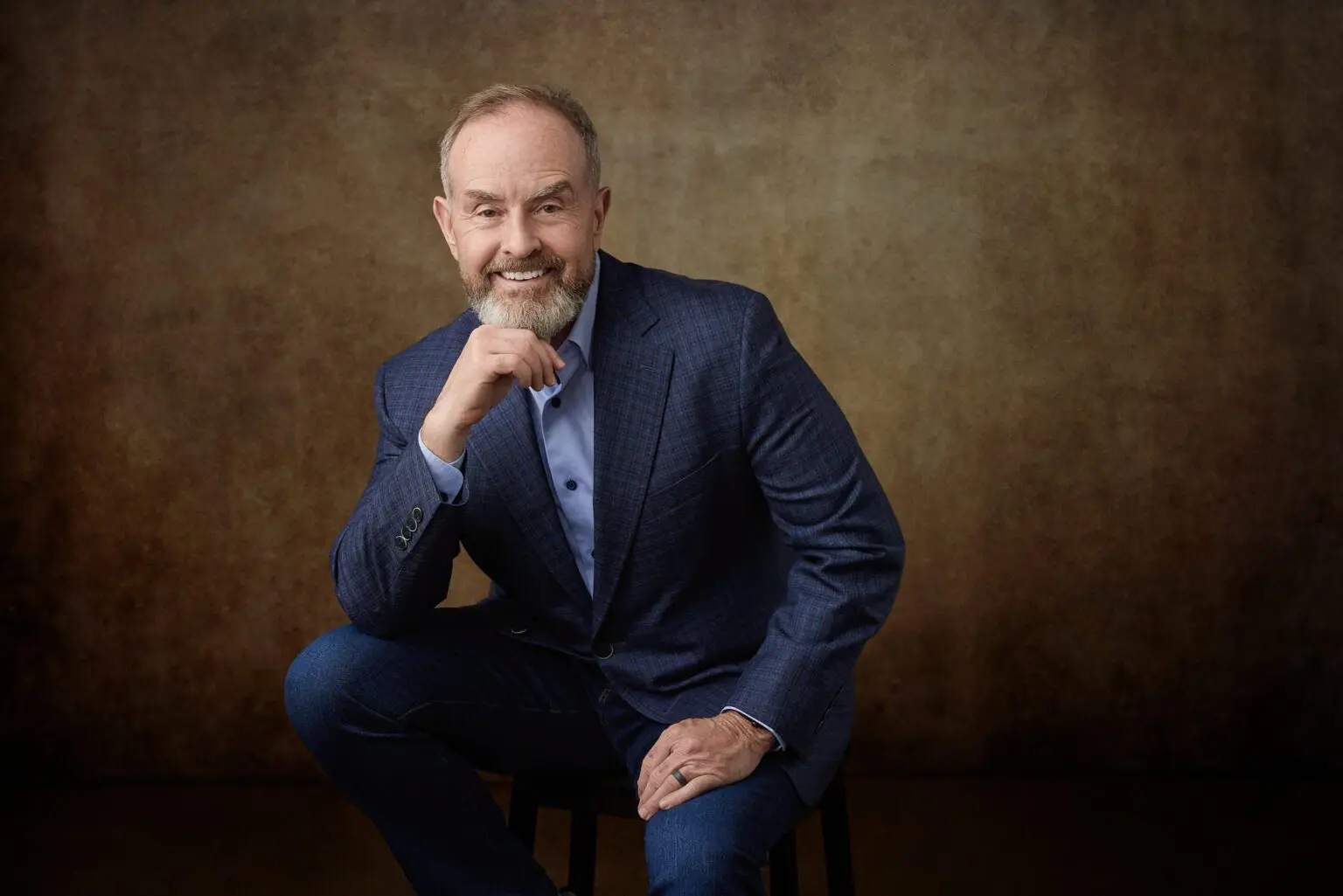 A formal business portrait sitting on a chair in WASIO faces studio